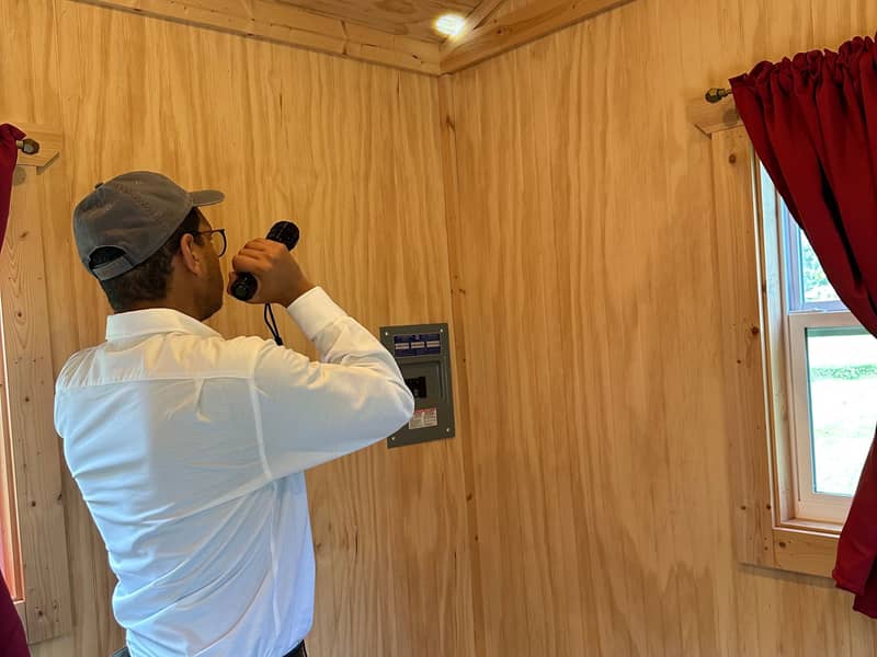 Technician inspecting a shed with a flashlight